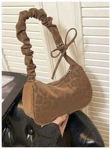 Detail of leopard print suede shoulder bag featuring a pleated strap and bow accent