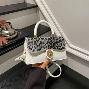 Leopard print patchwork handbag with gold clasp and white handle on a stylish background