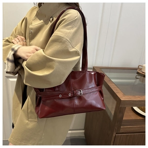 Detail of dark red glossy leather shoulder bag with silver buckle and sleek strap