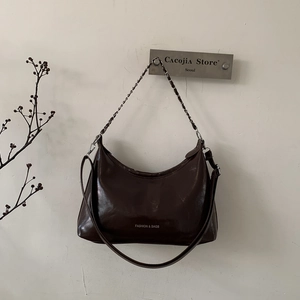 Détail du sac hobo marron foncé avec chaîne dorée et gravure de texte tendance