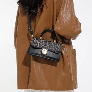 Chic leopard print patchwork crossbody bag with gold twist lock shown on a model
