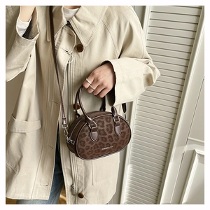 Close-up of leopard print Boston bag with top handles on a trench coat model