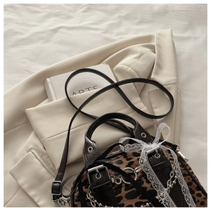 Detail of leopard print crossbody bag with silver chains and white lace bow decoration