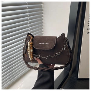Détail du sac à bandoulière marron foncé avec poignée tressée et chaîne à fleurs