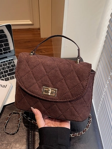 Deep coffee quilted crossbody bag with gold chain strap in a cozy indoor office setting