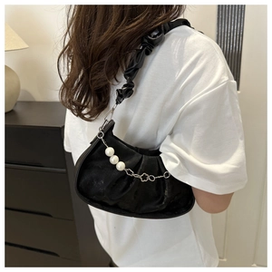 Close-up of black ruched cloud bag with decorative pearl and metal flower chain