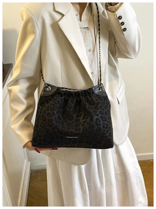 Detail of black leopard print tote bag with silver chain strap and pleated design on model