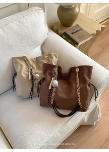 Detailed macro view of minimalist bucket bags with gold chain straps and suede texture