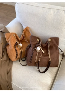 Detail view of suede tote bags with golden chain straps and drawstring closure