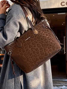 Grand sac cabas léopard marron avec logo en métal, porté sur un manteau en laine