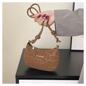 Detail of leopard print shoulder bag featuring Creative Cat text and sleek PU texture