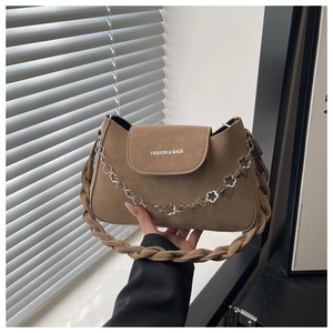 Détail d'un sac kaki avec poignée tressée et chaîne métallique à motif floral chic