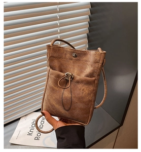 Détail d'un sac à bandoulière en toile marron avec boucle métallique et cordon serrage