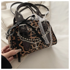 Detail of leopard print mini bag featuring silver chains and metallic cross pendants