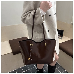 Detail of dark brown oil wax leather tote bag with glossy finish and decorative charms