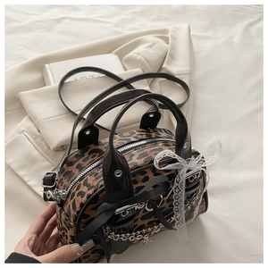 Detail of leopard print handbag with black bows and silver chain on a beige blazer