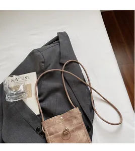 Gros plan du mini sac bandoulière en velours côtelé marron avec détail d'anneau