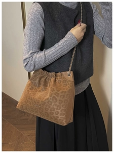 Detail of leopard print tote bag featuring metallic chain strap and gathered closure