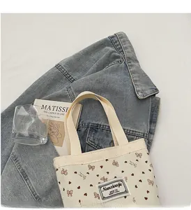 Detail of corduroy handbag with heart print and brand label on white surface