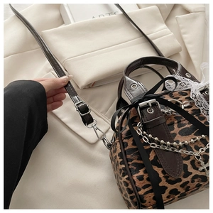 Detail of leopard print crossbody bag with silver chains, crosses, and lace trim