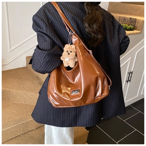 Detail showing high-gloss brown leather tote bag texture with a cute puppy keychain