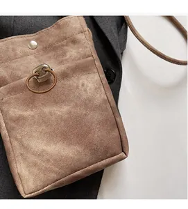 Gros plan sur un sac de téléphone en toile marron avec texture sergé et bouton pression en métal