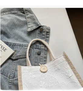 Close-up of floral embroidery on linen handbag with a decorative round wooden button