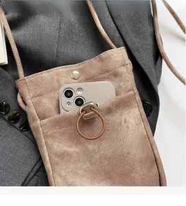 Détail du sac bandoulière en toile marron avec anneau métallique et poche téléphone