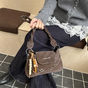 Sac à bandoulière marron foncé avec sangle tressée, chaîne florale et breloque ethnique