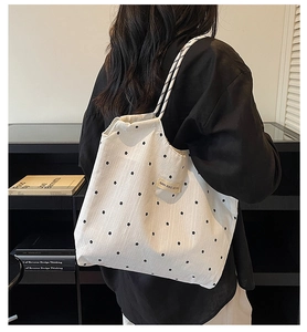 Detail of white canvas tote bag featuring delicate black floral print and brand label