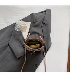 Détail du compartiment intérieur spacieux d'une petite sacoche bandoulière beige pour téléphone