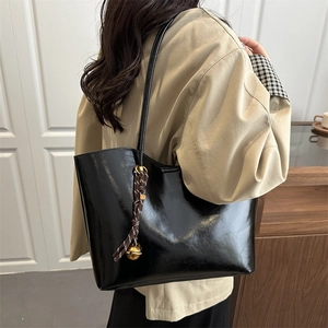 Black oil wax leather tote bag with decorative charms shown on a model for daily commute