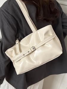 Minimalist cream glossy patent leather tote bag with silver metal buckle on a shoulder