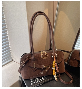 Detailed view of dark brown suede handbag with brand stamping and pearl bead charm