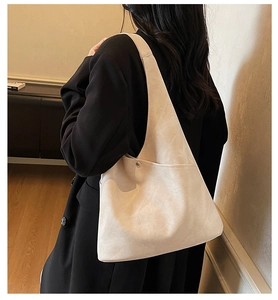 Detail of cream matte suede bucket bag with silver metal button and side pocket