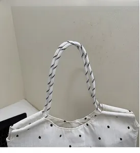 Close-up of white mesh tote bag featuring black floral patterns and sturdy woven handles