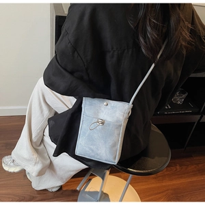 Détail du sac de téléphone en toile bleu clair avec cordon métallique et bandoulière