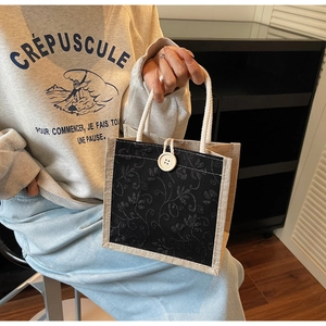 Linen tote bag detail with black lace floral embroidery and white woven rope handles