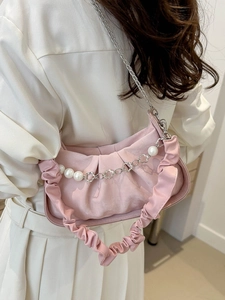 Pink pleated cloud bag with pearl and floral chain shown on a model in white outfit