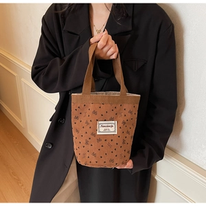 Detailed close-up of brown corduroy bucket bag featuring black bow and heart patterns