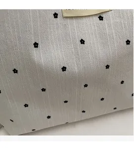 Detail of floral canvas bag showing pleated fabric texture and beige woven label