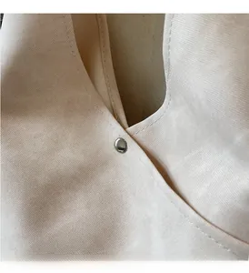 Detailed close-up of beige canvas bag showing precise stitching and silver metal rivets