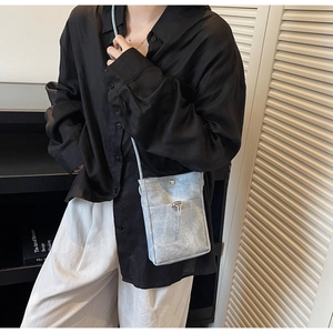 Détail du petit sac bandoulière bleu clair minimaliste sur modèle avec texture mate