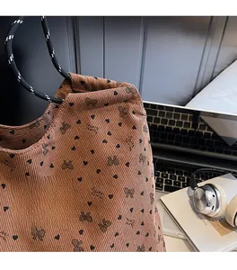 Close-up of brown corduroy tote with heart patterns and woven rope shoulder strap