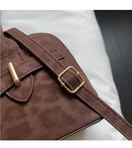 Detail of dark brown suede shoulder bag strap with premium golden metal buckle