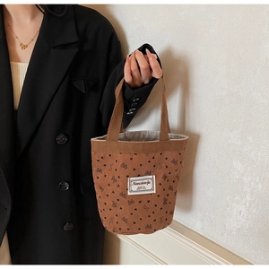 Detail view of brown corduroy handbag featuring black heart and bow prints on fabric