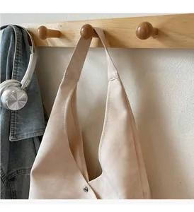 Close-up of minimalist beige canvas hobo bag with durable strap and silver snap closure