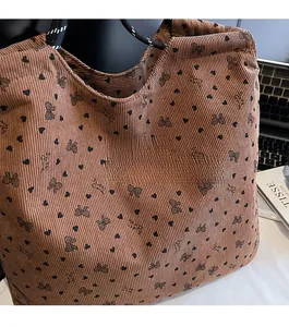 Close-up of brown corduroy tote with heart patterns and woven rope handles on desk