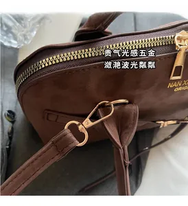 Detailed close-up of brown suede bag texture with premium gold zipper and hardware