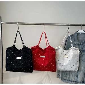 Detail of floral canvas tote bags in black, red, and white with cotton strap texture